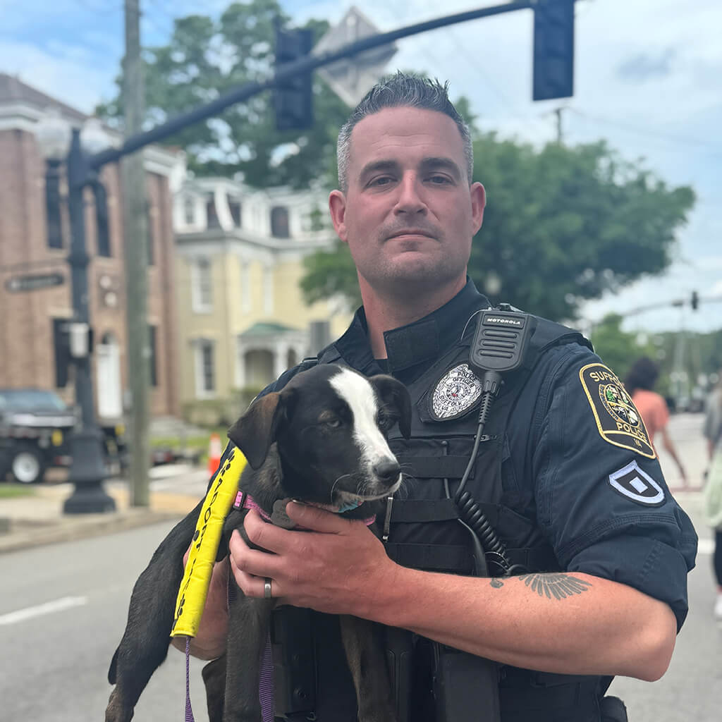 Suffolk policeman holds adoptable dog on the street.