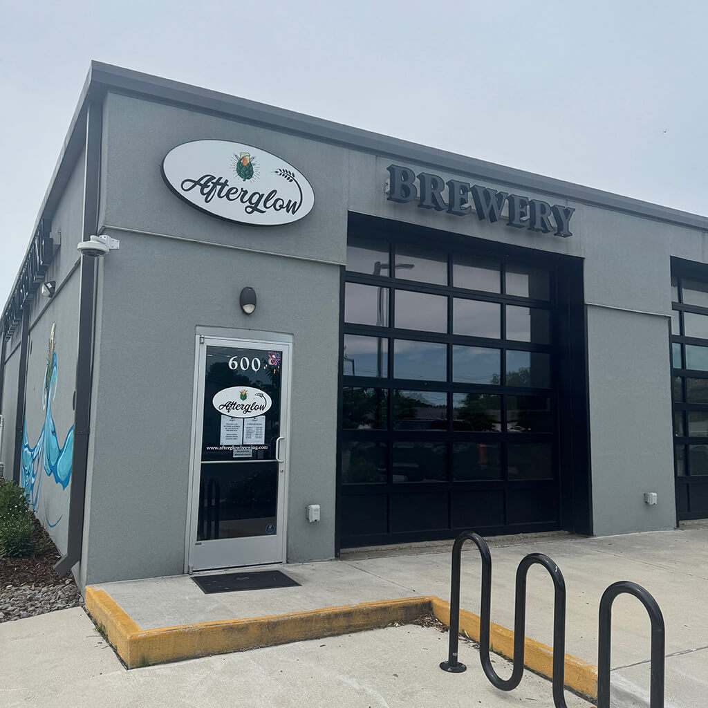 Afterglow Brewery building is a grey brick building with black trim and an oval sign over the door