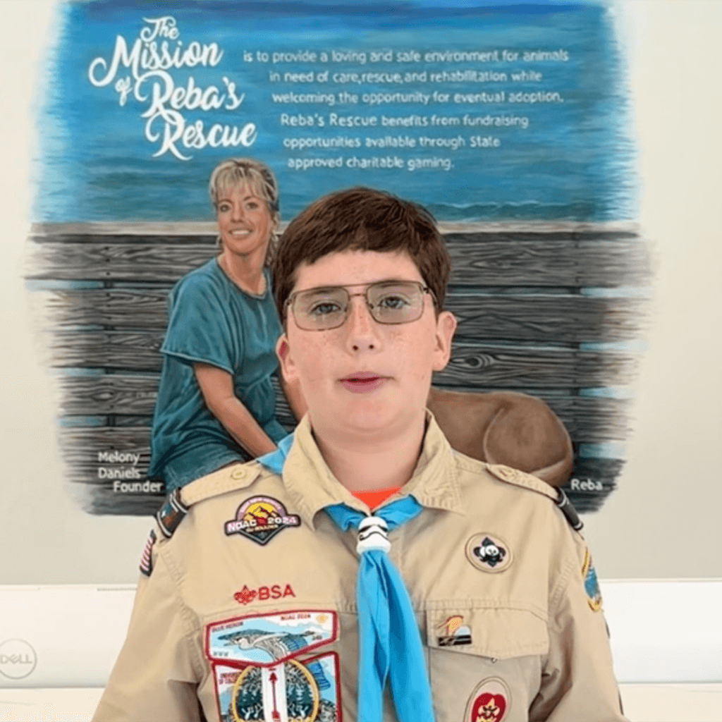 Life scout Trey in his uniform explaining this project infant of Reba's mission mural.