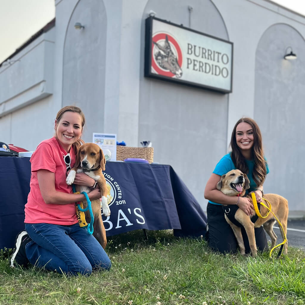 Two ladies and two dogs in front of Burrito Perdido building.