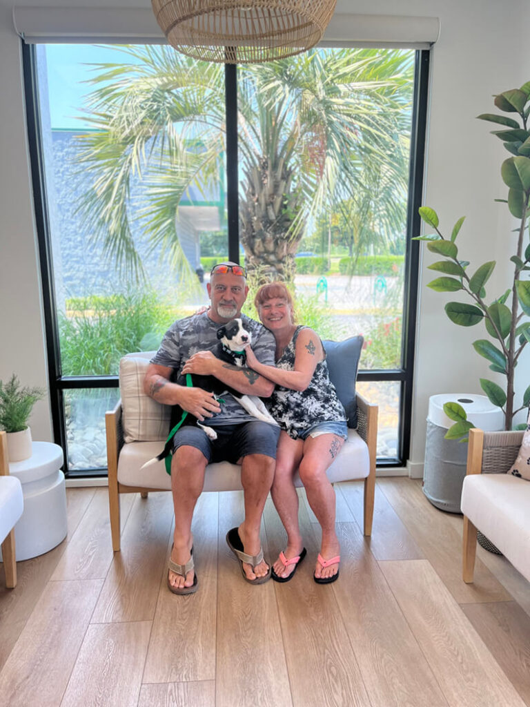 This couple look very happy to be holding a black and white puppy.