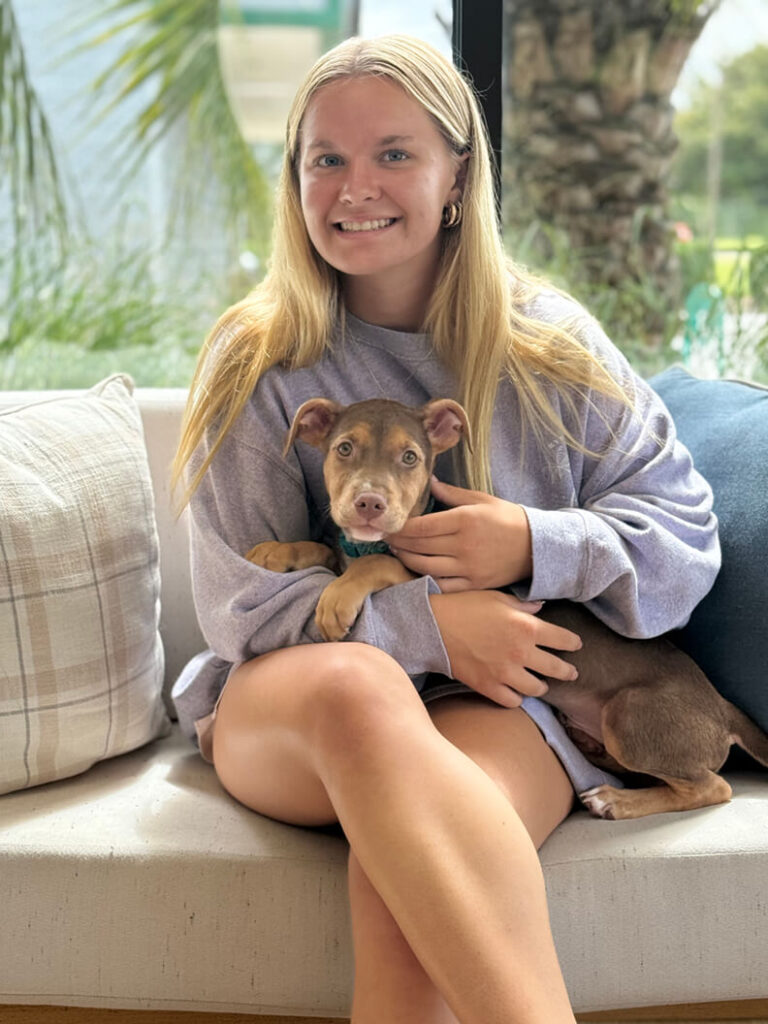 A blonde lady holding a brown puppy called Blaze.