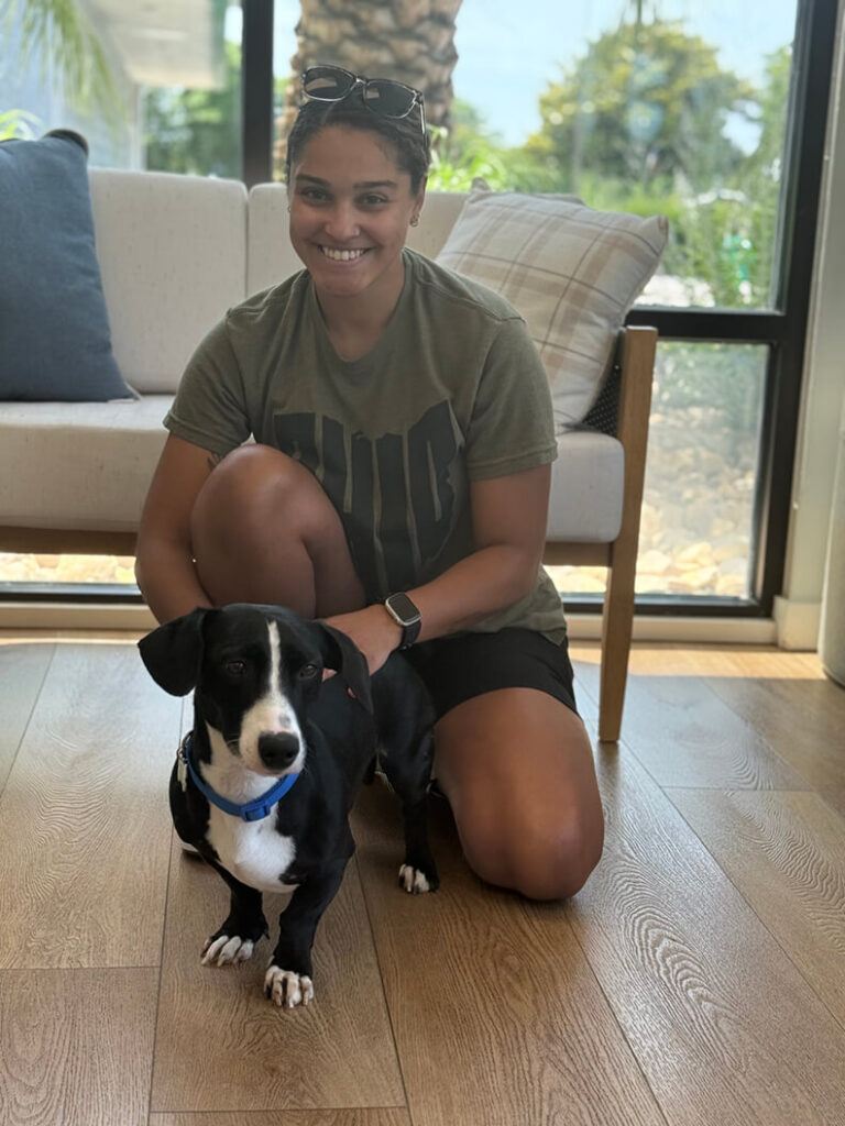 This lady is kneeling down next to Bruno, a short, black and white dog.