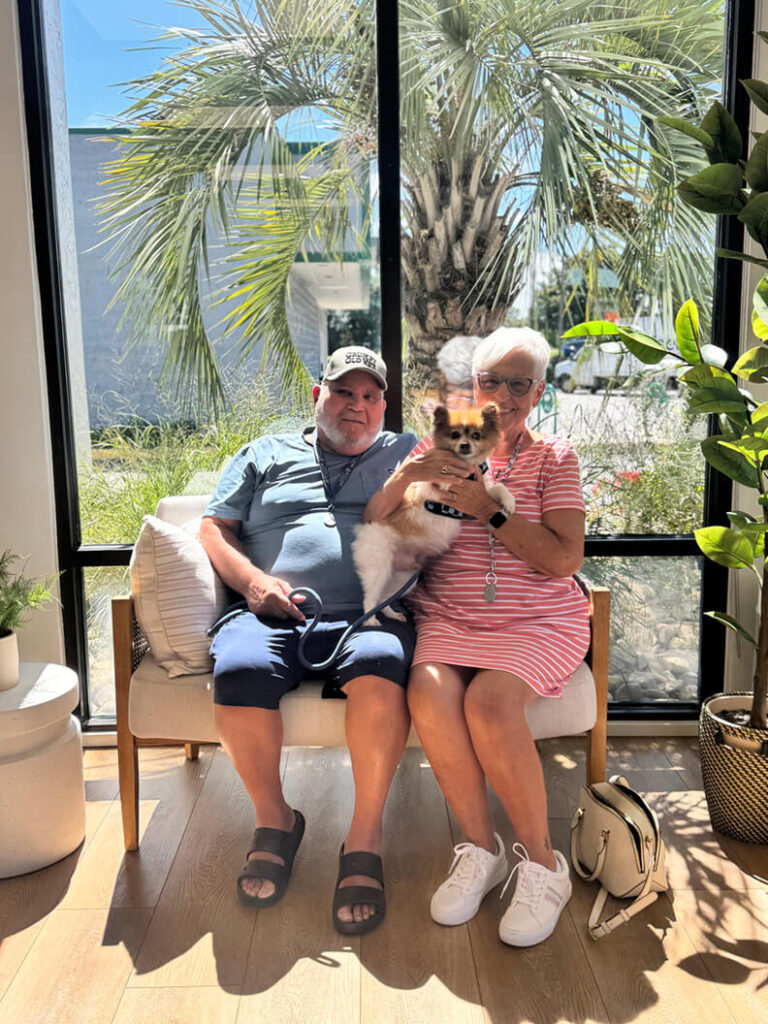 Older couple holding a small brown and white dog called Chip.