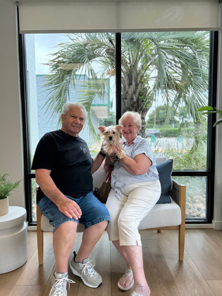 Older couple holding small tan dog.