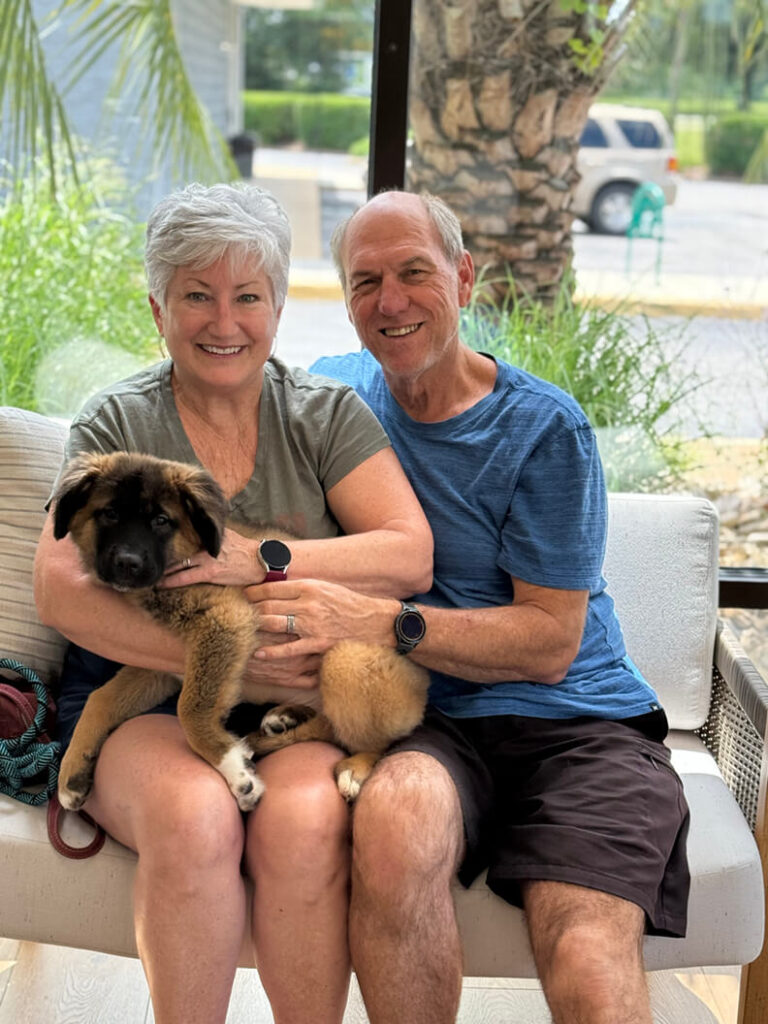 Couple holding a brown and black puppy that was part of the Dumpling gang.