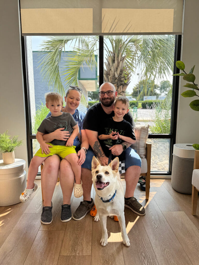 Family of four pose with a happy Orlo, their new tan dog.
