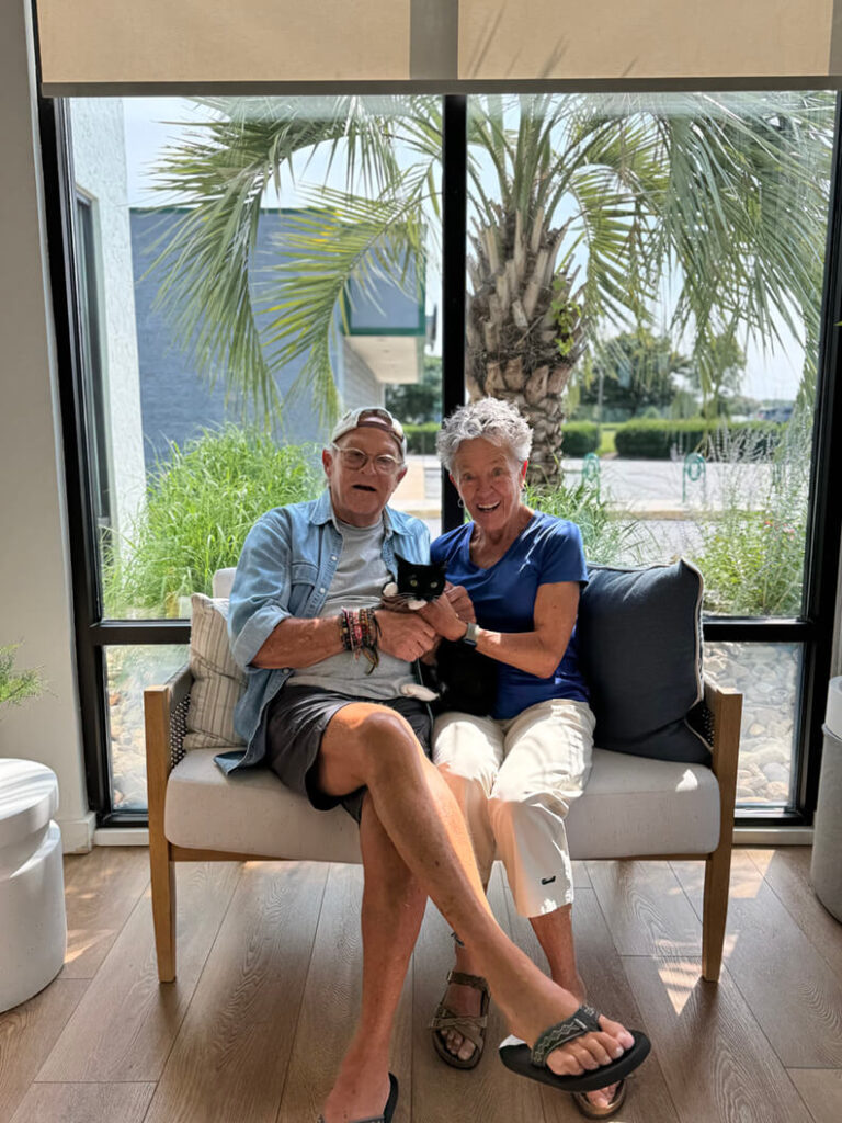 Happy couple holding their new black and white kitten that looks like Pete the Cat.