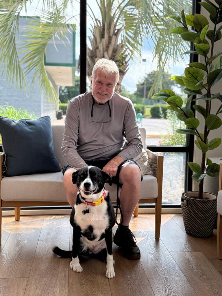 Older gentleman is sitting with his new black and white adult dog.