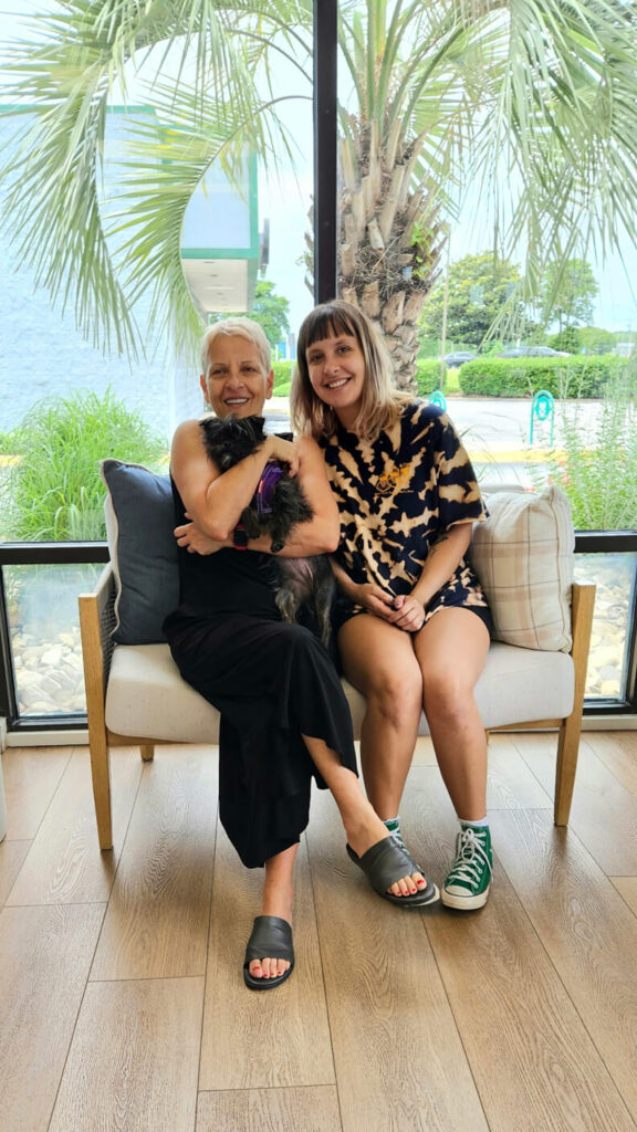 Two ladies holding a little dog with long black hair.