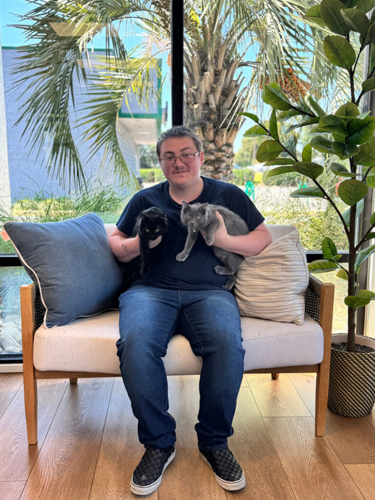 One person with a black cat and a gray cat. August 2025 adoption of Toothless and Astrid.