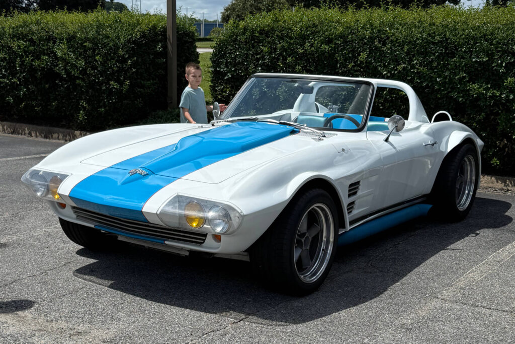 blue and white car in parking lot with little boy looking inside it