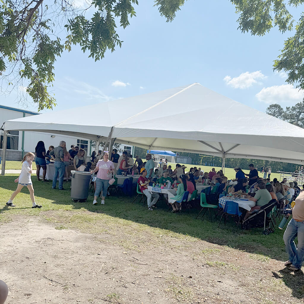Group of people under a tent having a picnic outside at the church