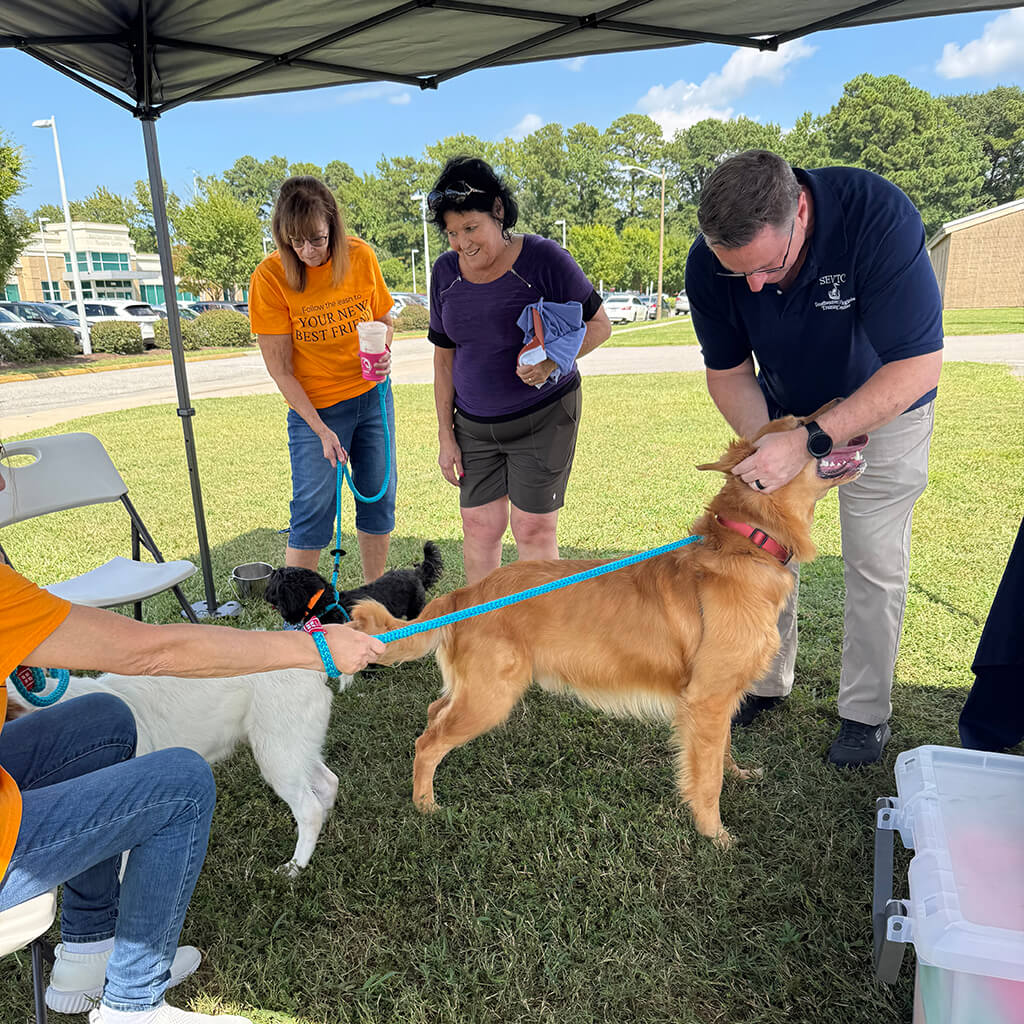 A couple visited the tent to meet the black dog and the golden retriever mix.