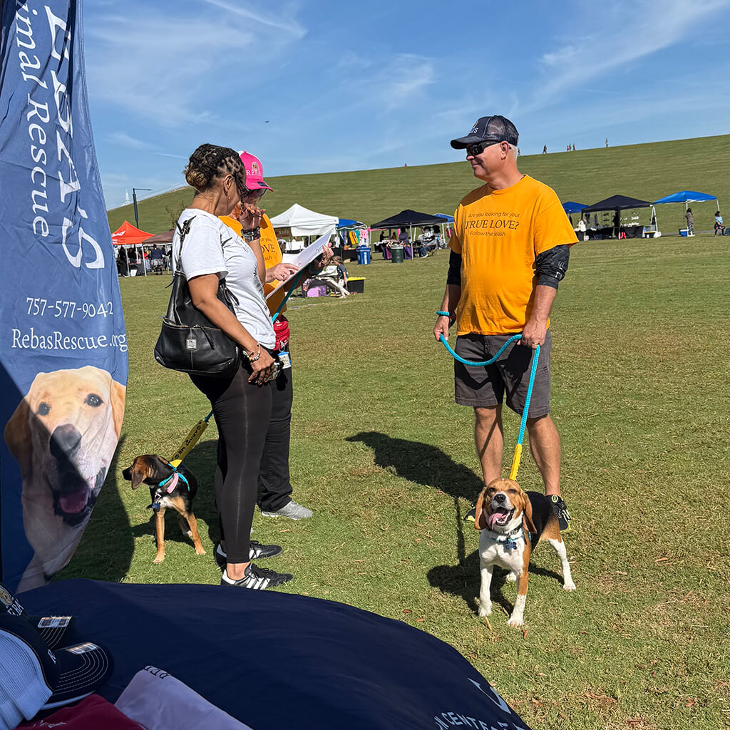 A visitor stops by Reba's tent and the volunteer is talking to them about the pets available for adoption.