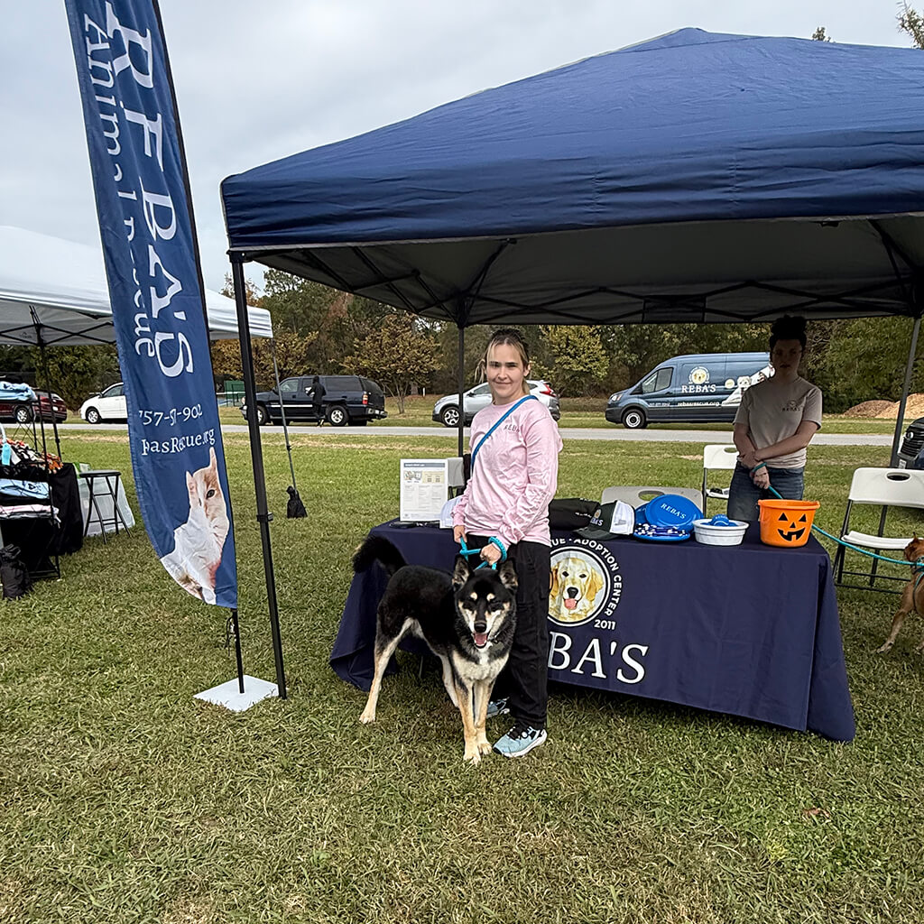 Reba's tent with employees and black dog in front