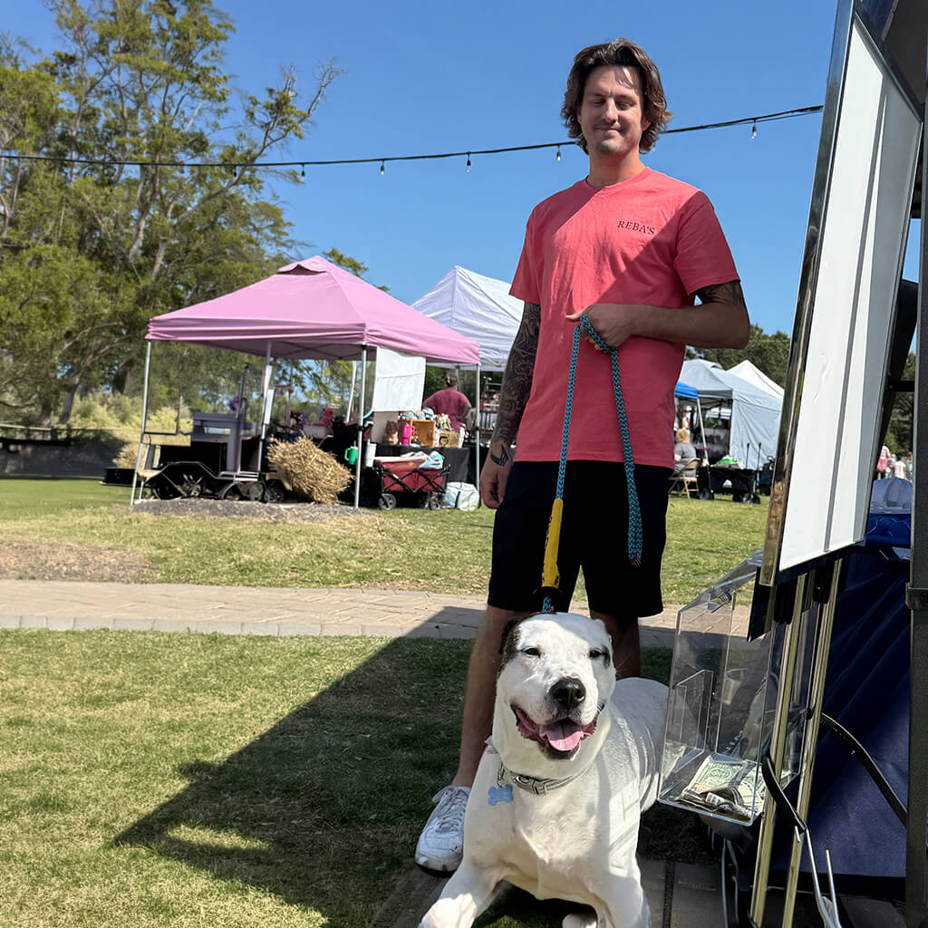 Staff member poses with a white adoptable dog