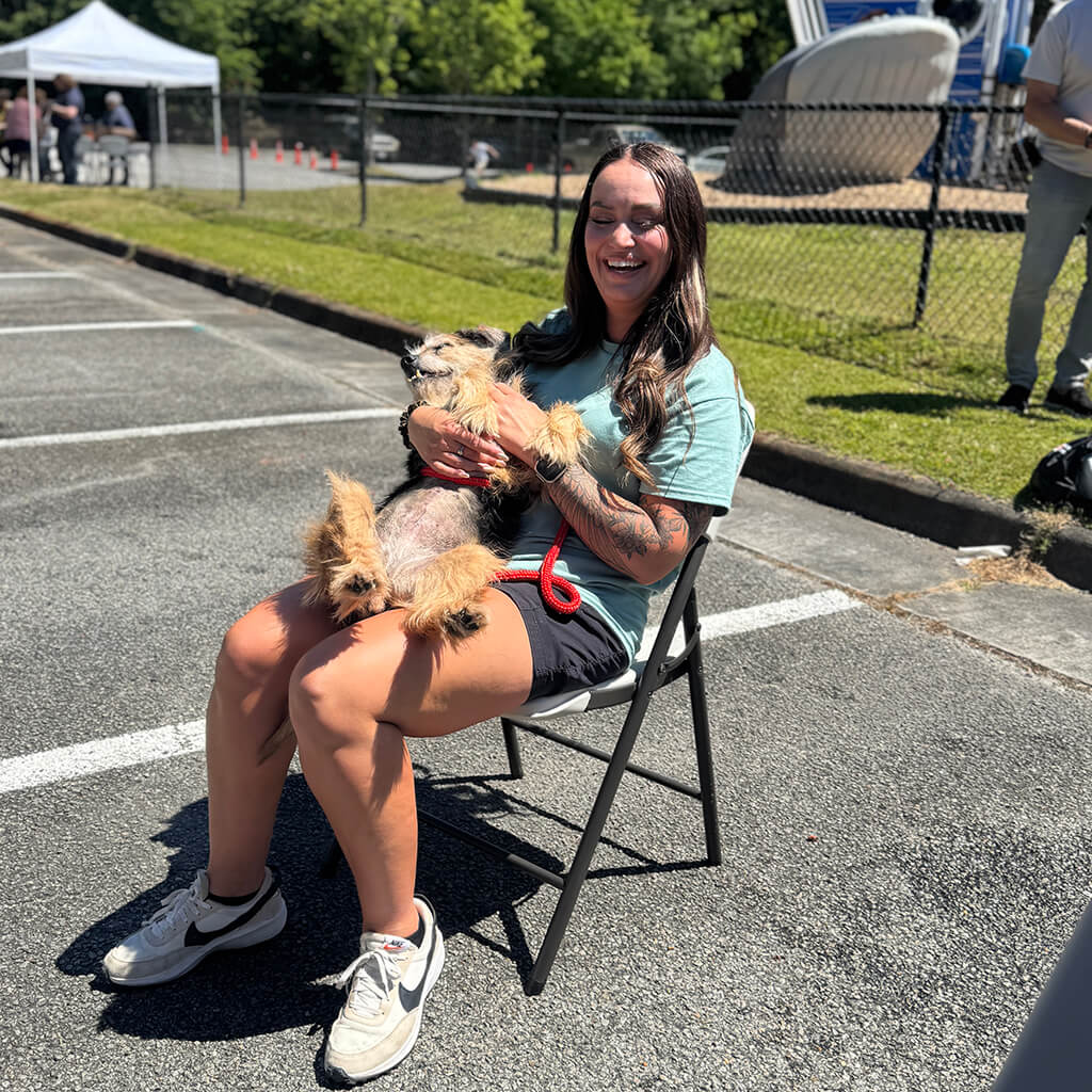 Scruffy dog laying on his back in volunteers lap at Blessing of the pets