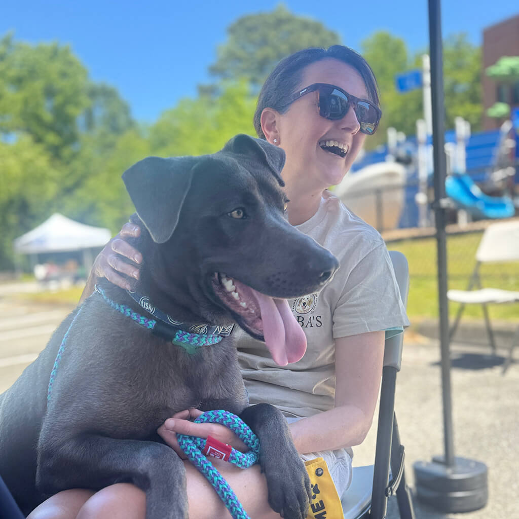 Big gray dog on volunteers lap at Blessing of the pets