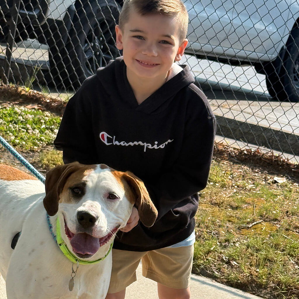 Young boy poses with White dog with brown ears