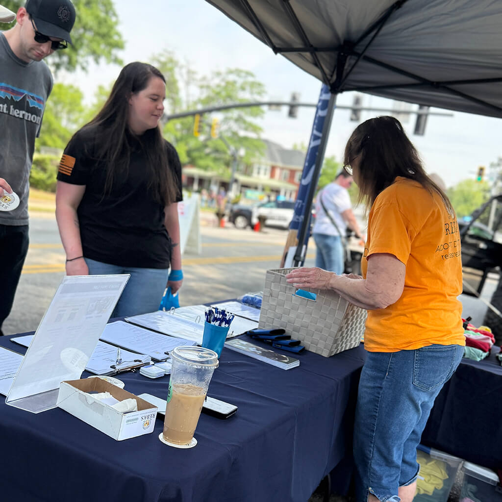 Volunteer at booth helping a couple visitors
