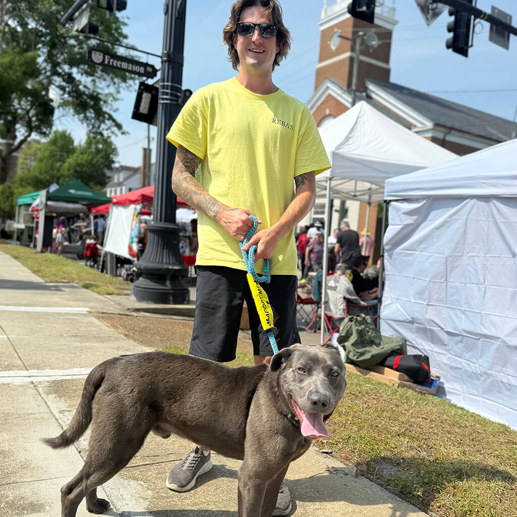 Staff in yellow shirt with gray dog