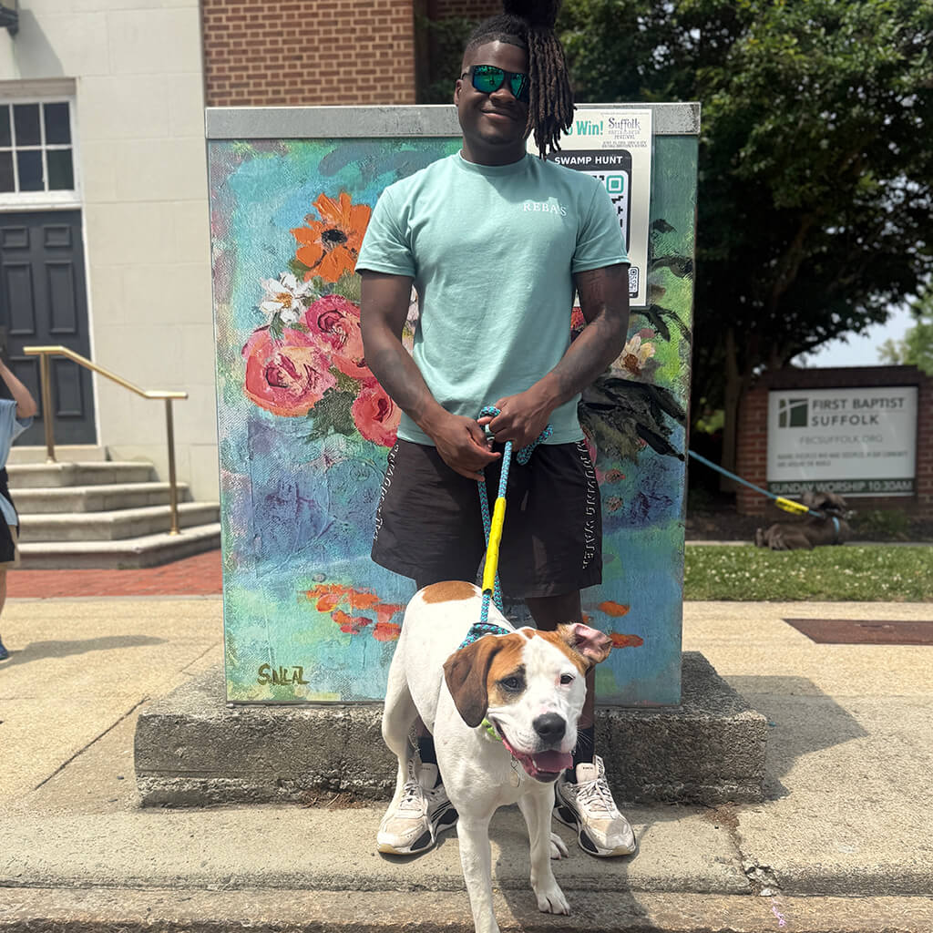 white dog with brown ears poses with staff member