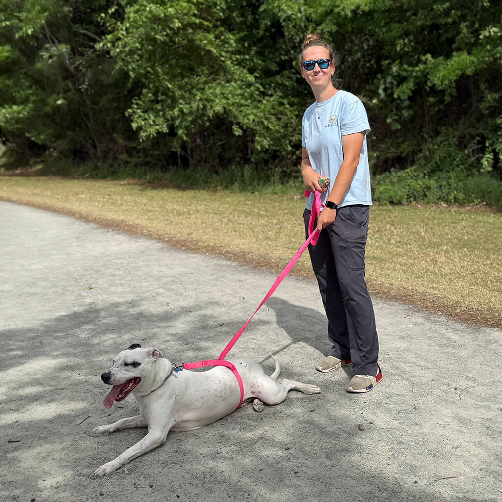 May 8th Road Trip with the Coast Guard - Staff member and white dog relaxing on the path