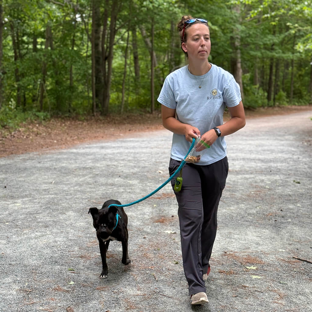 May 8th Road Trip with the Coast Guard - staff walking in the woods with a black dog